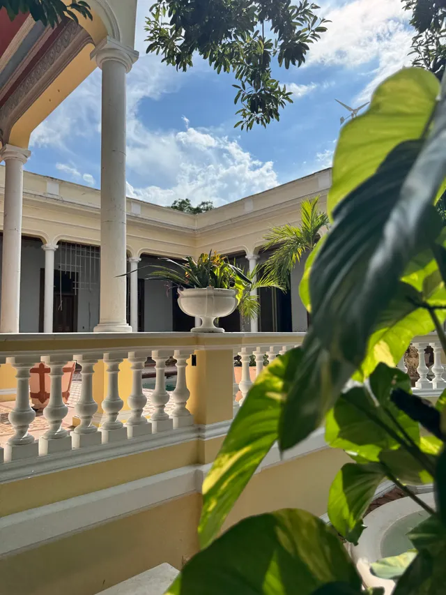 The central area's balustrade with a white planter urn, among columns and foliage