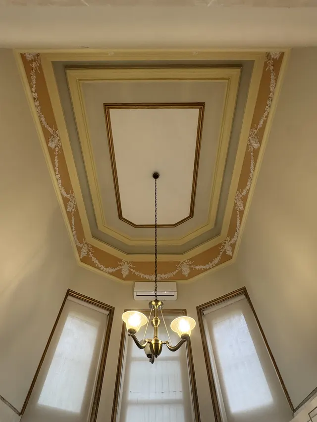 Hand-painted ceiling mouldings and light fixture in the men's bathroom
