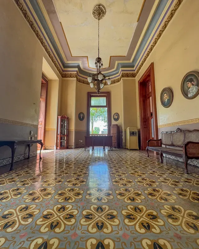 Vestíbulo con piso de mosaico, candil y retratos familiares