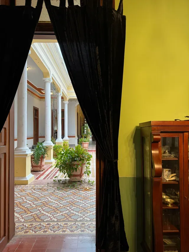 View through a black velvet curtain toward the central corridor with columns and potted plants