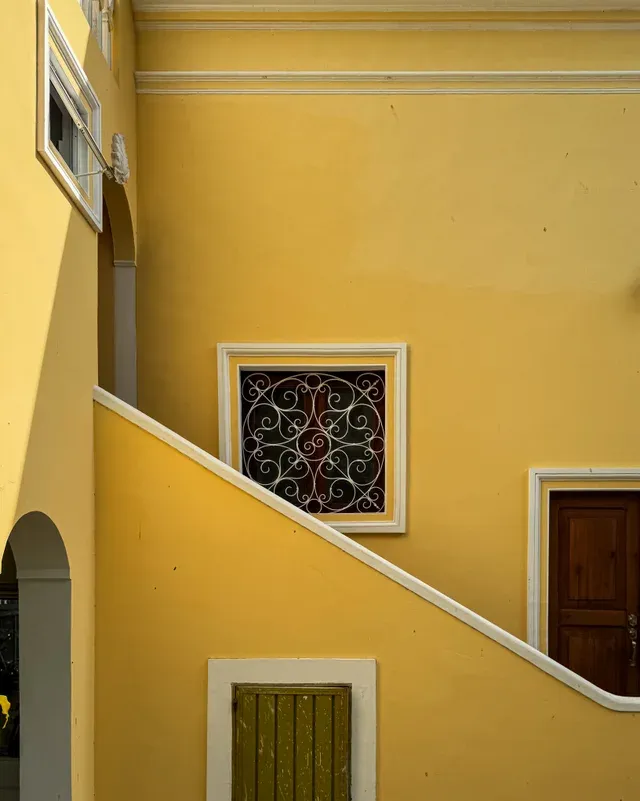 Detail of the yellow façade with an exterior staircase and a decorative window grille