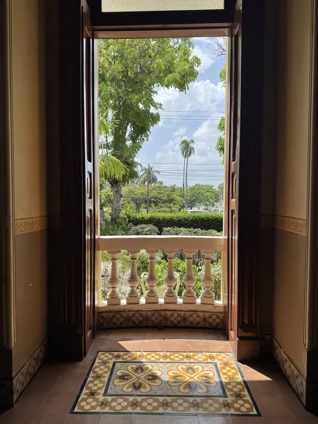 Vista desde el interior hacia el jardín, con vegetación tropical y balaustrada de piedra
