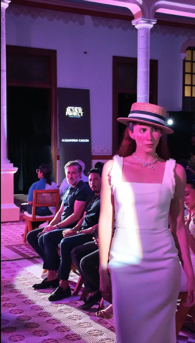 Modelo con vestido blanco frente al backdrop de Runway Project