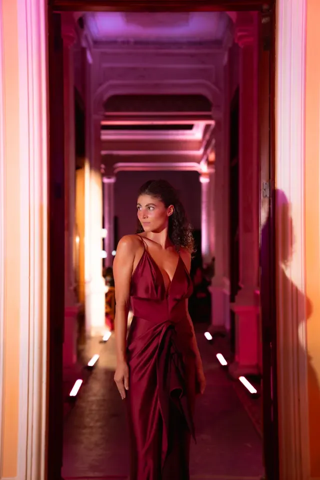 Modelo con vestido satinado vino caminando por el corredor iluminado